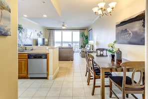 A spacious living area with a dining table, chairs, and a kitchen area with a dishwasher. - Lake view condo! Near Disney! (Orlando)