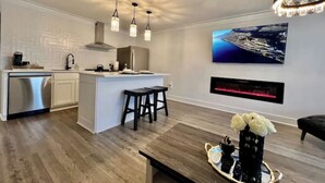 Una cocina moderna con una isla central, taburetes de bar, una mesa de comedor y una chimenea.