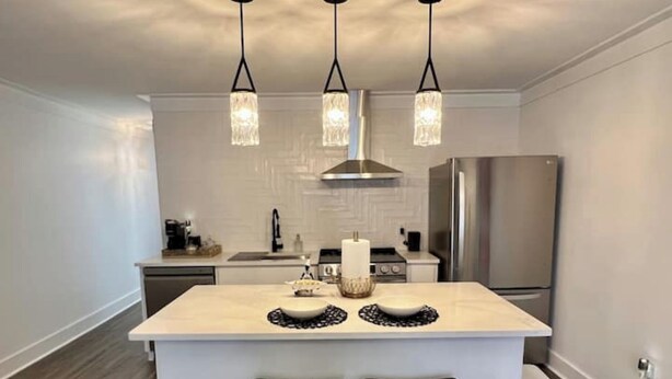 Una cocina moderna con una isla central, electrodomésticos de acero inoxidable e iluminación colgante.