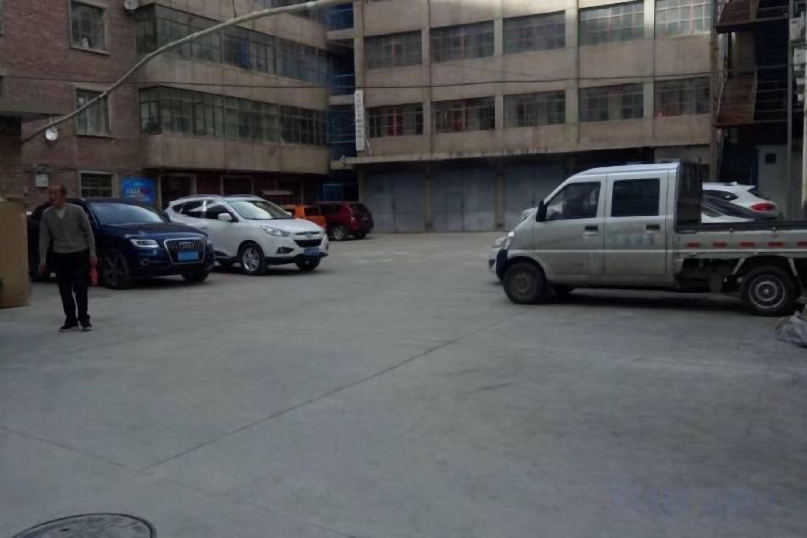 A parking area with a white pickup truck and several cars.