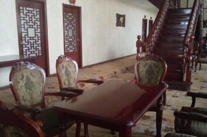 Una habitación con una mesa y sillas de madera, una escalera y puertas tradicionales.
