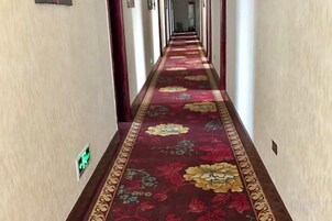 Un pasillo de hotel con piso alfombrado y pared de color claro.