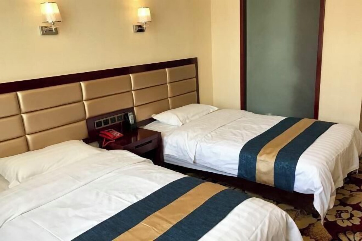 Ein Hotelzimmer mit zwei Betten, jeweils mit Kopfteil und Nachttischen.