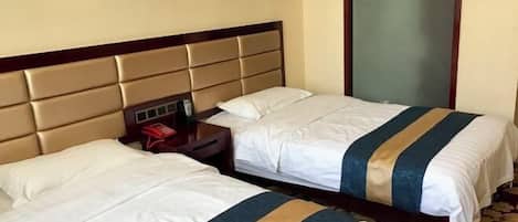 A hotel room with two beds, each with a headboard and bedside tables.