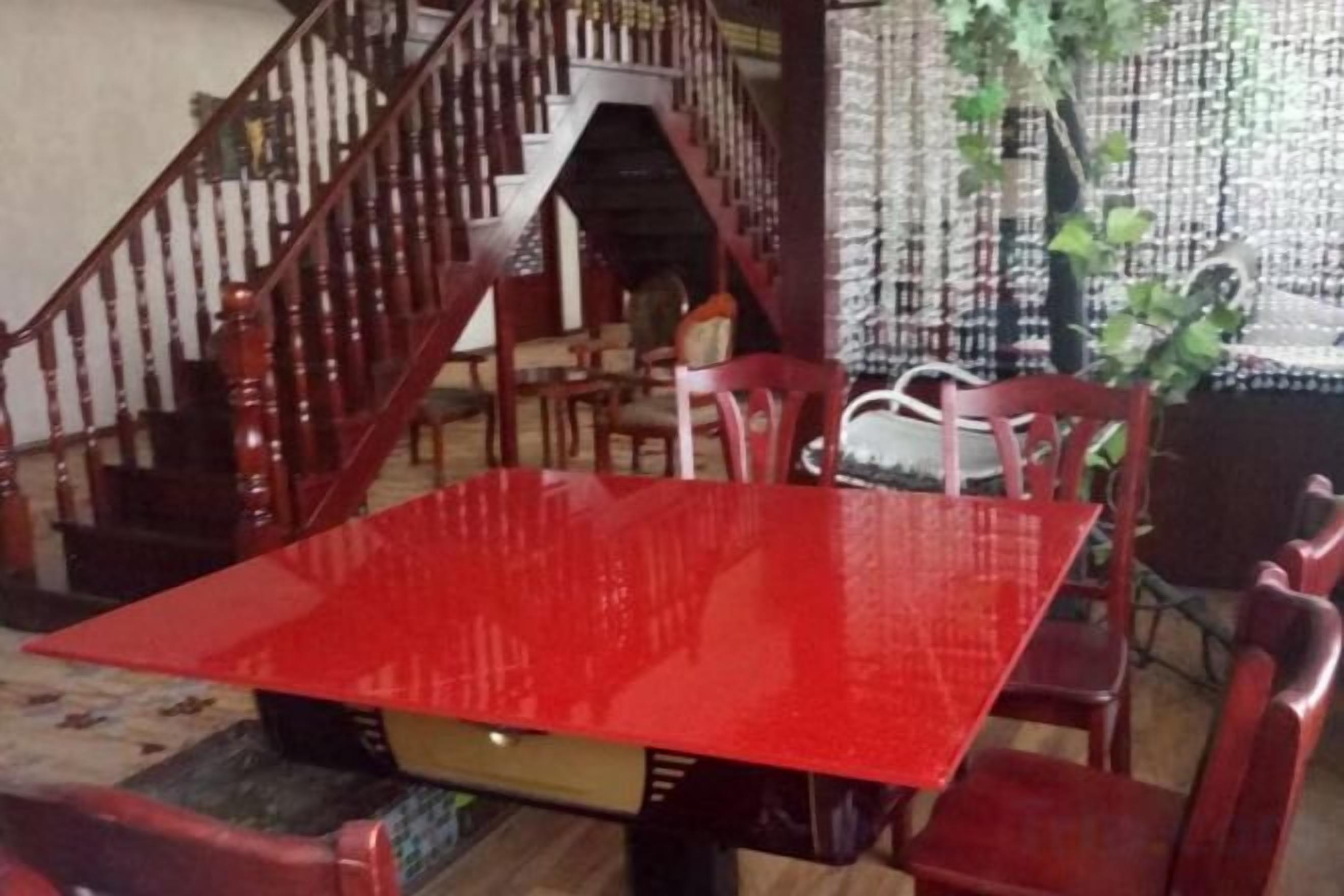 A dining area with a red table and chairs, a staircase, and a plant.