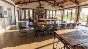 A spacious kitchen with a large island, a stone fireplace, and ample natural light from large windows.