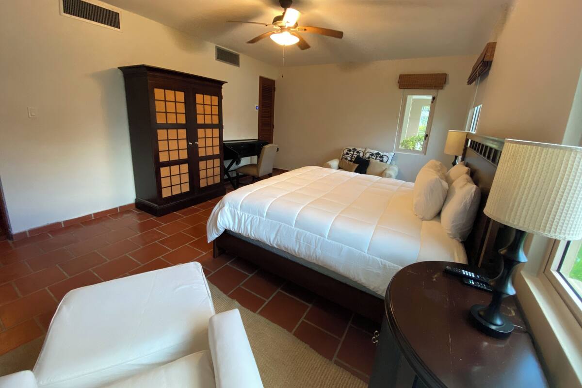 A bedroom with a bed, a desk, a chair, a wardrobe, and a ceiling fan.