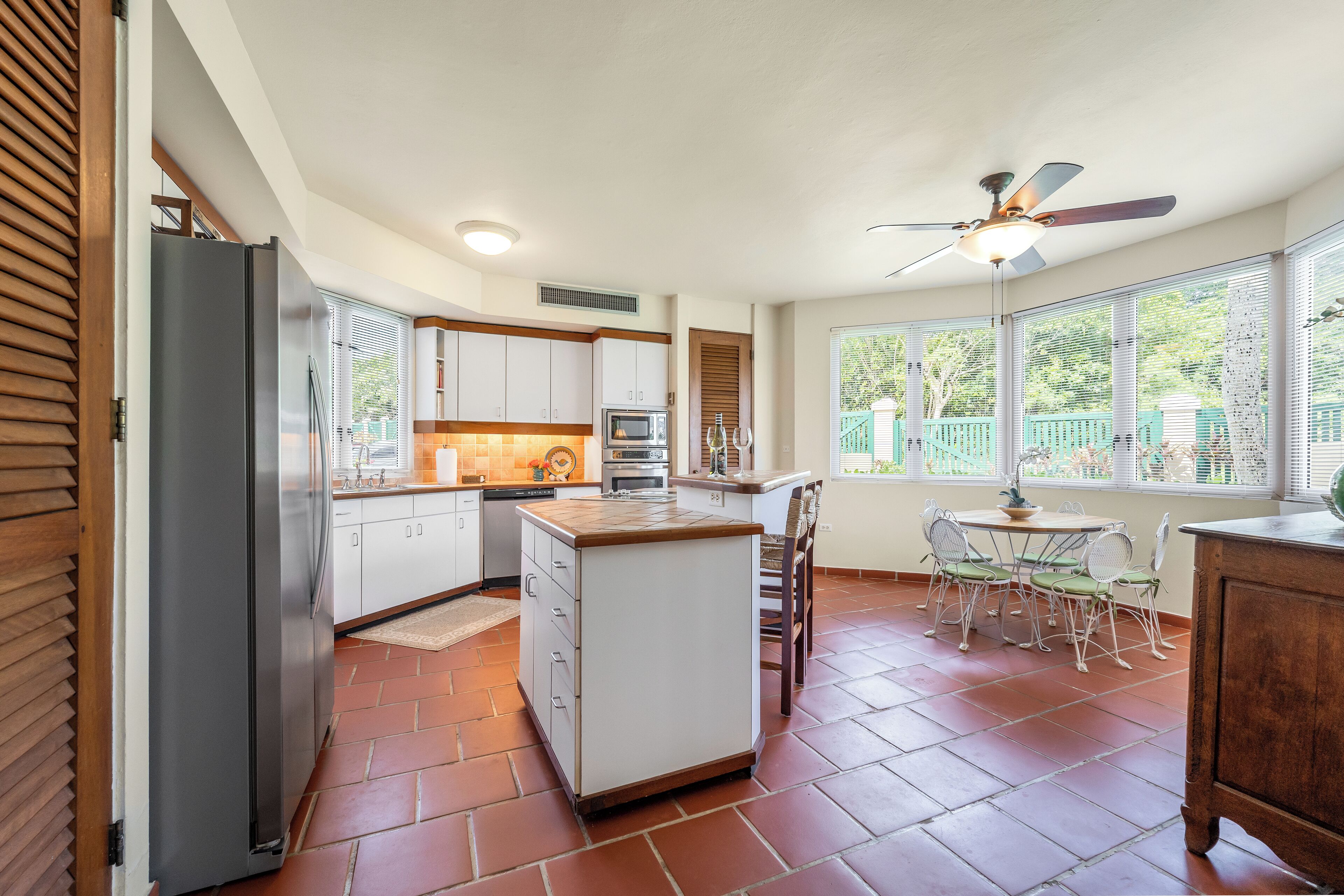 A kitchen with a central island, white cabinets, and a dining area with a table and chairs.