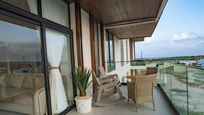 A balcony with a sofa, a rocking chair, and a table. - Luxury Retreat Condo 3BR Cap Cana Punta Cana (Punta Cana)