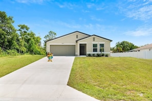 A single-story house with a garage, a front lawn, and a clear sky.
