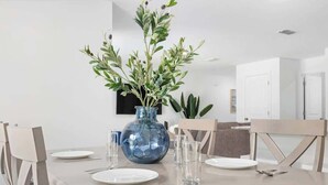 A dining table set with plates, cutlery, and a blue vase with green foliage. - Spacious House with Garden | Ideal for Long Stays (Spring Hill)