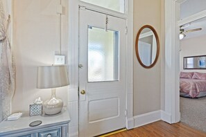 A bedroom with a bed, a bedside table, a lamp, and a mirror.