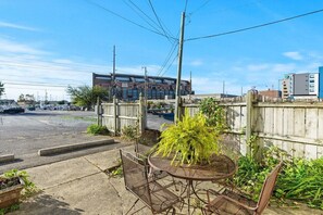 A patio with a metal table and chairs, a wooden fence, and a building labeled "STADIUM" in the background.