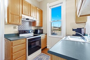 A compact kitchen with wooden cabinets, a built-in microwave, a stove, and a sink.