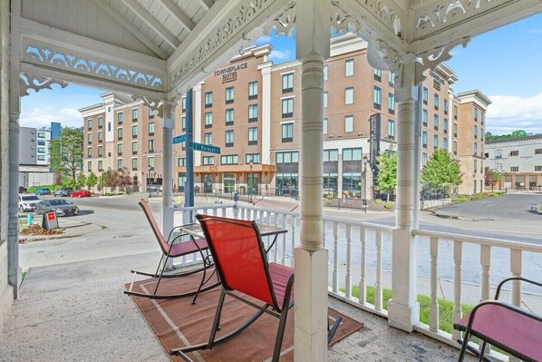 A hotel with a covered outdoor seating area, a brick building in the background, and a street view.