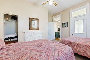 A bedroom with two beds, a white fireplace, a ceiling fan, and a door leading to a bathroom. - 2 BR Next To Lucas Oil - Walk to Conventions! (Indianapolis)