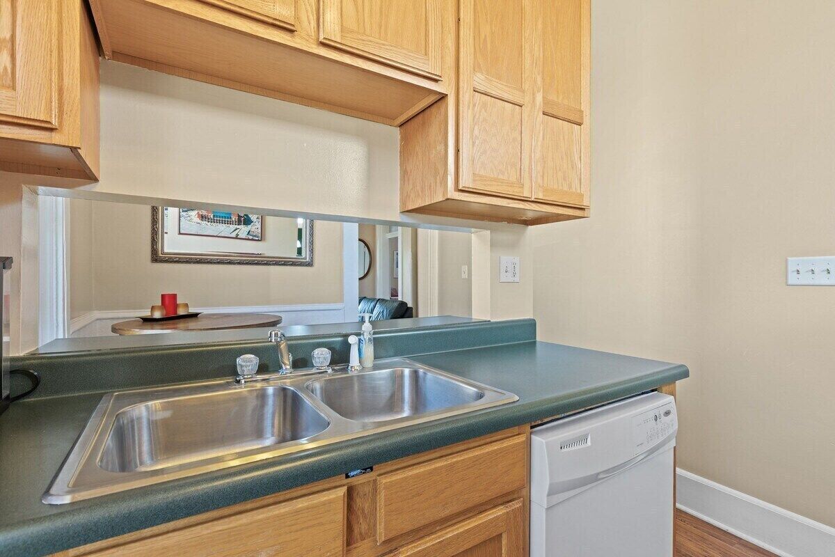 A kitchen with wooden cabinets, a double sink, and a dishwasher.