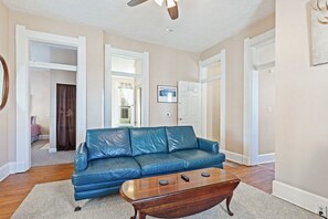 A living room with a blue leather sofa, a wooden coffee table, and a ceiling fan.
