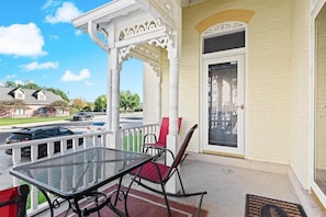 A covered porch with a table and chairs, a white railing, and a door with a window. - 2 BR Next To Lucas Oil - Walk to Conventions! (Indianapolis)