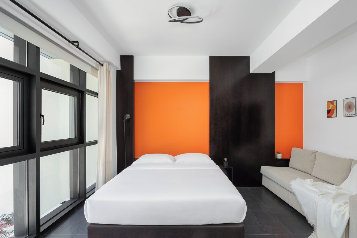 Un dormitorio moderno con una cama grande, un sofá y una ventana con cortinas.