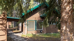 A log cabin with a stone pathway leading to the entrance, surrounded by trees. - Evergreen Escape -Fishing - Boating - Yellowstone - Hiking, Atving & Kayaking. (Island Park)