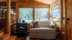 A cozy cabin interior with a sofa, a fireplace, and wooden walls. - Evergreen Escape -Fishing - Boating - Yellowstone - Hiking, Atving & Kayaking. (Island Park)