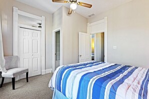 A bedroom with a bed, a chair, and a ceiling fan.