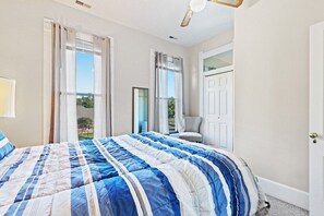 A bedroom with a large bed, a chair, and a door.