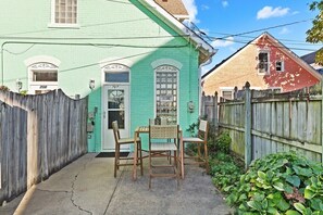A small, enclosed patio area with a wooden fence, a green door, and two wooden chairs.