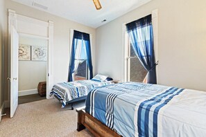 Une chambre avec deux lits, une porte et une fenêtre avec des rideaux bleus.