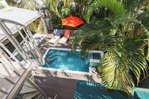 A rooftop pool with lounge chairs, surrounded by palm trees and a red umbrella. - Knowles Main House with Pool (Key West)