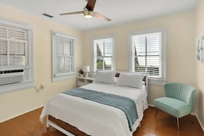 A bedroom with a bed, a ceiling fan, and a window with blinds.