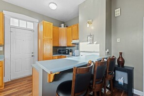 A compact kitchen with wooden cabinets, a built-in microwave, and a small dining area with a table and chairs.