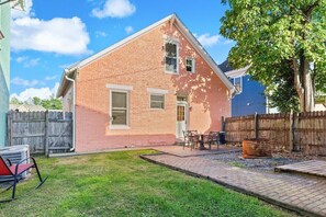 A two-story brick house with a small backyard, a wooden deck, and a fenced area. - Entire 3BR Home Steps to Stadium (Indianapolis)