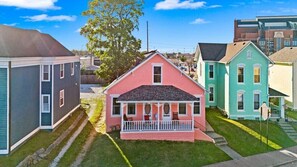 A row of colorful houses with a central pink house featuring a porch.