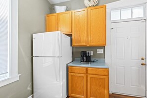 A kitchen with wooden cabinets, a white refrigerator, and a coffee maker on the countertop.