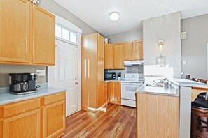 Une cuisine avec des meubles en bois, un réfrigérateur blanc, une cuisinière et un four à micro-ondes.