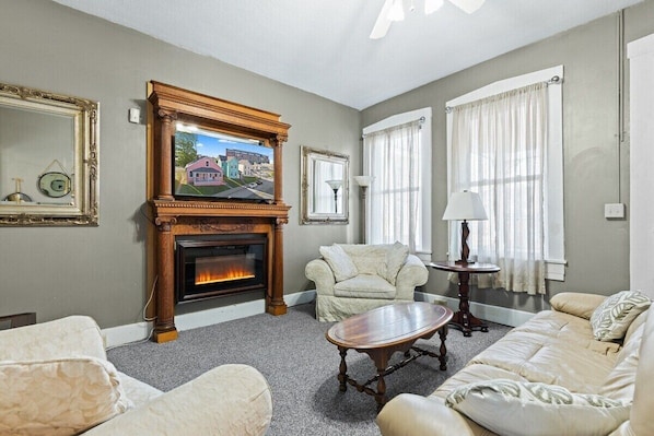 A living room with a fireplace, a sofa, a chair, and a table.