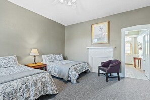 Une chambre avec deux lits, une chaise, une lampe et une cheminée.