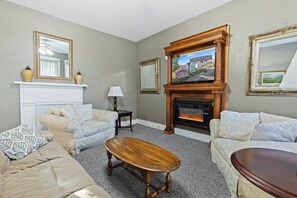 A living room with two sofas, a wooden coffee table, a fireplace, and framed pictures on the walls. - Entire 3BR Home Steps to Stadium (Indianapolis)