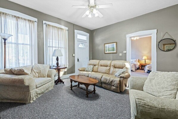 A living room with a beige sofa, a wooden coffee table, and a ceiling fan.