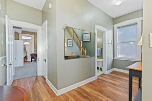 A hallway with wooden flooring, a staircase, and a door leading to another room. - Entire 3BR Home Steps to Stadium (Indianapolis)