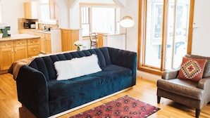 A living room with a dark blue sofa, a brown leather armchair, and a patterned rug. - Historic 8th Ave Home - 5 BDRM Downtown Bozeman (Bozeman)