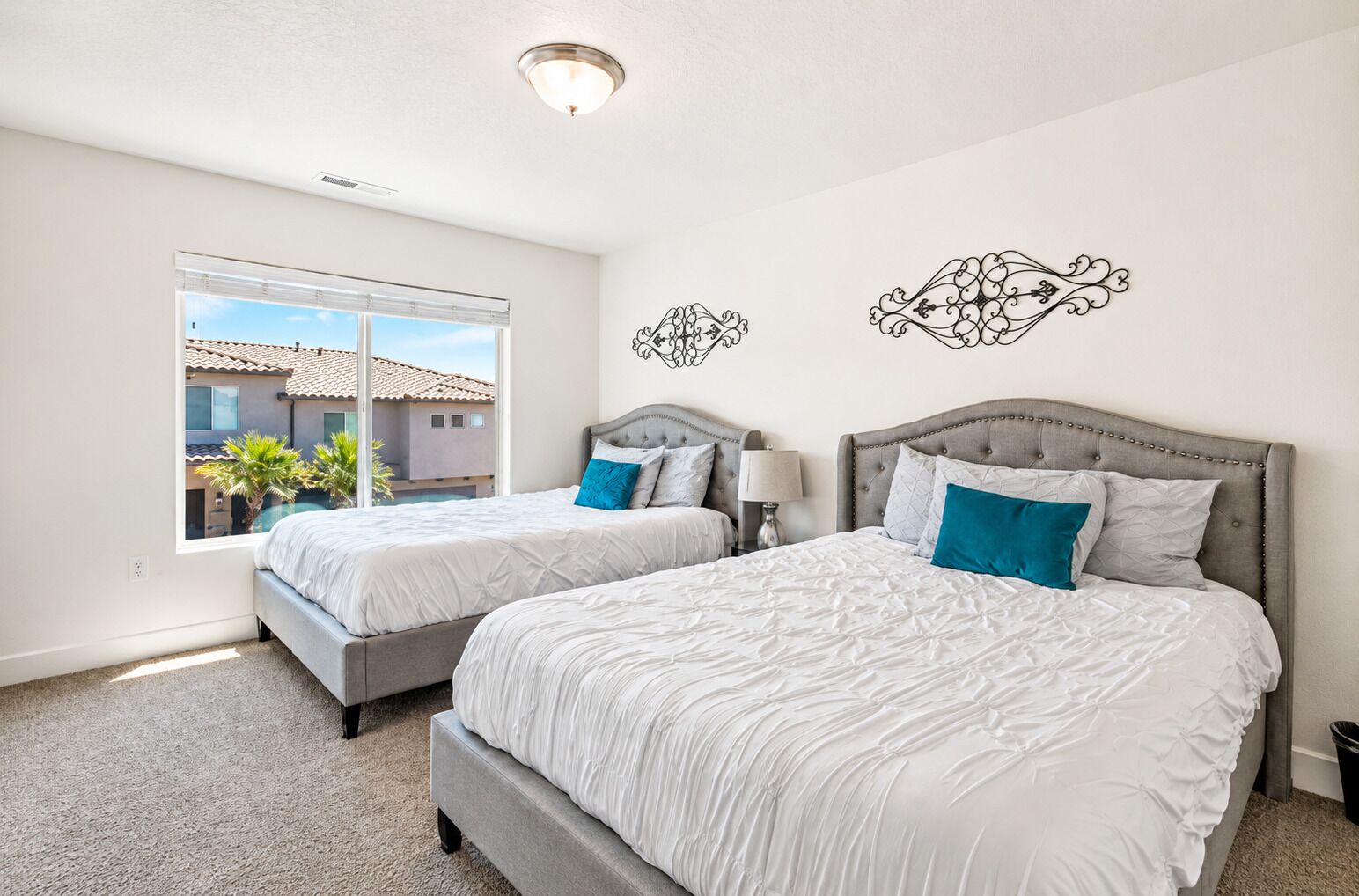 A bedroom with two beds, a window, and decorative wall art.