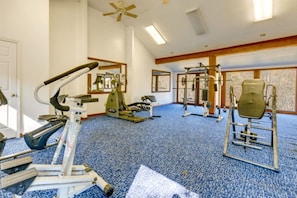 A gym with various exercise equipment, a ceiling fan, and large windows. - Village 37 Stone Cabin with Private Hot Tub (Bryson City)