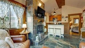Ein gemütliches Wohnzimmer mit Kamin, Ledersofas und einer Essecke mit Barhocker.