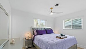 A bedroom with a bed, nightstand, dresser, and a ceiling fan. - Incredible 4-bedroom home in Tequesta FL with AC, WiFi and absolute comfort. (Tequesta)