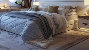 Une chambre moderne avec un grand lit, une tête de lit dotée d’un éclairage intégré et une fenêtre offrant une belle vue.