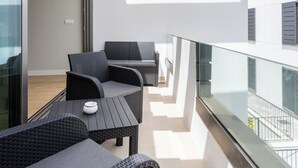 A modern balcony with wicker furniture and a glass railing overlooking a cityscape. - Home2Book Modern Bright Apt Abades, Pool & Terrace (Abades)
