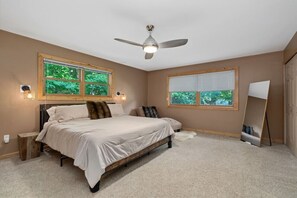 A bedroom with a bed, two windows, a ceiling fan, and a standing mirror. - Charlevoix Retreat on Private Acre Near Lake MI (Charlevoix)